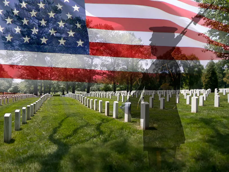 Rows of white gravestones in a military cemetery, green grass and trees in the background. A translucent American flag and a saluting soldier honor those who served, serving as inspiration on Memorial Day for leaving your legacy of courage and sacrifice.